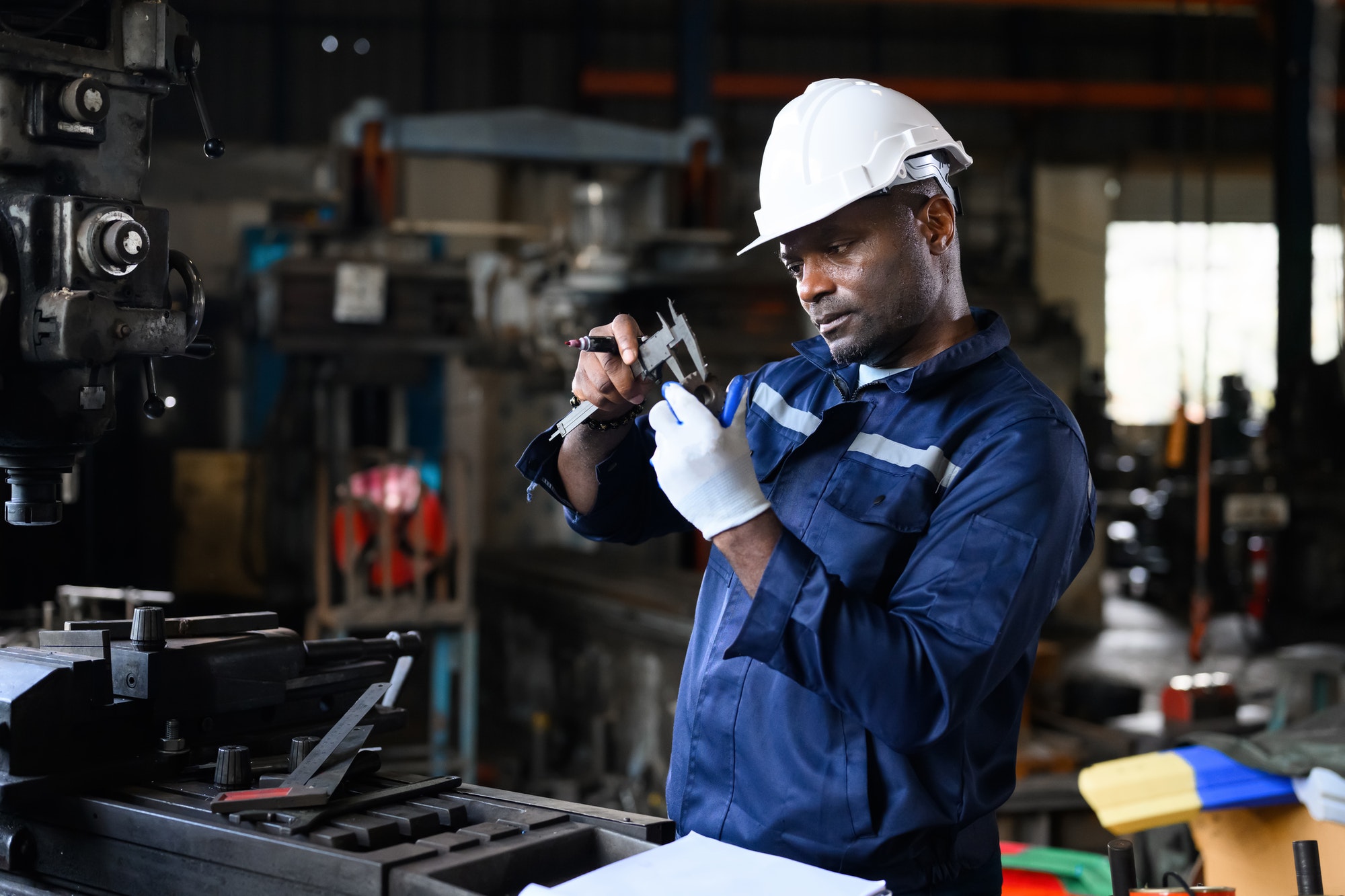 Professional male industrial worker in white hard hat working at manufacturing